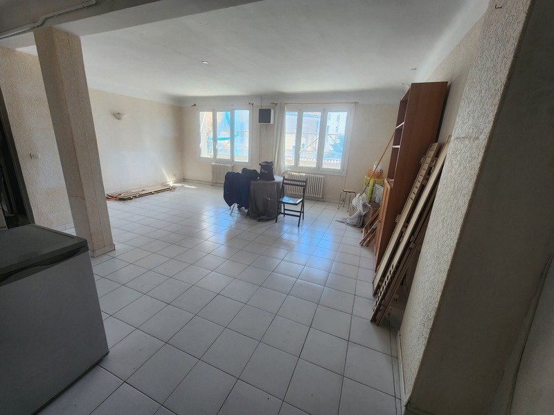 Le même séjour avant travaux : pièce vide, carrelage clair et murs nus.