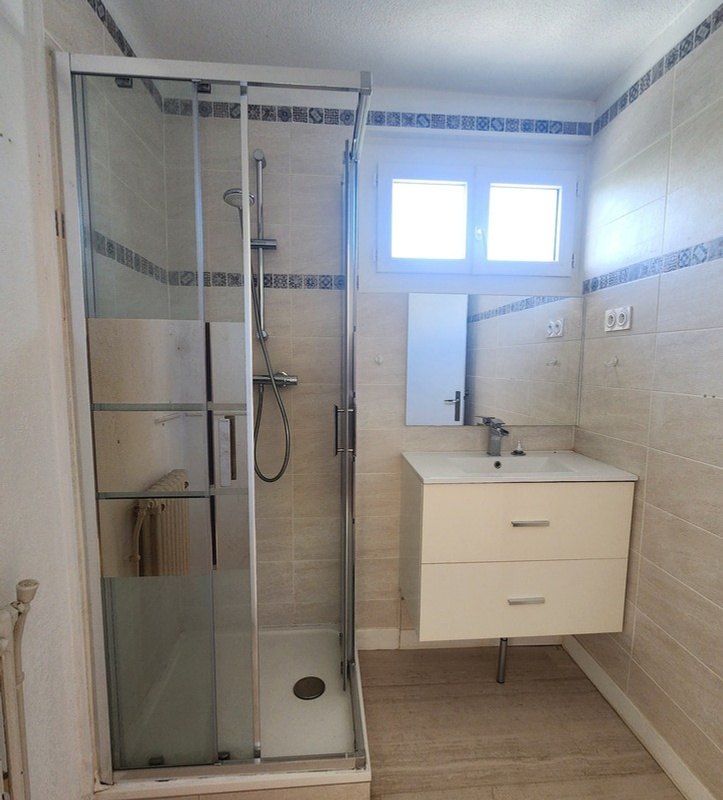 Salle de bain avant travaux : faïence claire à frise bleue.